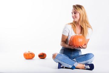 Halloween concept, happy Girl sitting on floor with pumpkins preparing for holiday, Jack lantern, funny and spooky pumpkin. Trick or treat tradition.