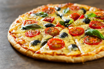 sliced Pizza Margherita or Margarita with Mozzarella cheese, tomato, olive. Italian pizza on wooden background