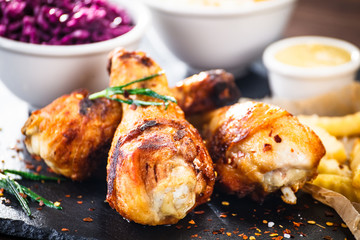 Grilled drumsticks with french fries and vegetables on wooden background