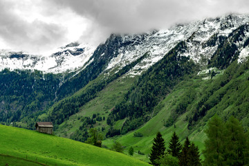 eine kleine Berghütte aus Holz, im Hintergrund Berge