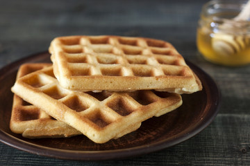 Viennese, Belgian waffles with honey on a white plate.