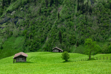 eine kleine Berghütte aus Holz, im Hintergrund Berge