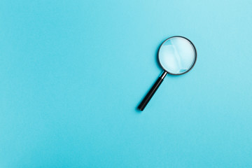 Magnifying glass on blue background. Top view. Flat lay. Copy space. Minimal creative concept. Blue...