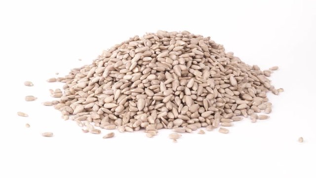 Heap of sunflower seed kernels poured out of a paper bag. Isolated on the white background. Close-up. Macro.