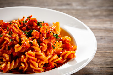 Pasta with tomato sauce and vegtables on wooden table