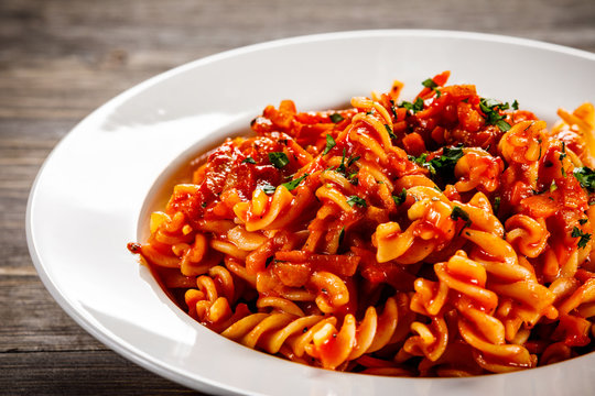Pasta with tomato sauce and vegtables on wooden table
