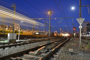 Fototapeta na wymiar Nighttime photograph of railway tracks. A passing train leaves light streaks.
