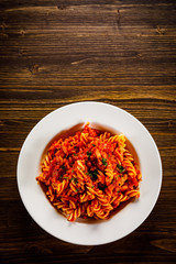 Pasta with tomato sauce and vegtables on wooden table