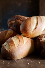 Delicious freshly baked bread on wooden background. Bakery product assortment with bread loaves, buns, rolls. Different kinds of bread 