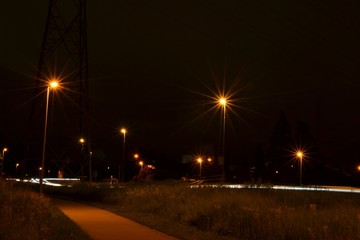 Nighttime photograph of a bicycle lane and a road near Vuntcomplex, Leuven, Belgium.