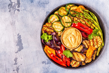 Grilled vegetables on a plate with sauce.