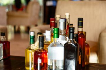 Many different bottles of alcoholic beverages are on the table.
