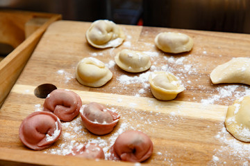 Raw dumplings (pelmeni) of different colors lie on the Board