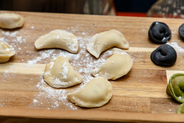 Raw dumplings (pelmeni) of different colors lie on the Board