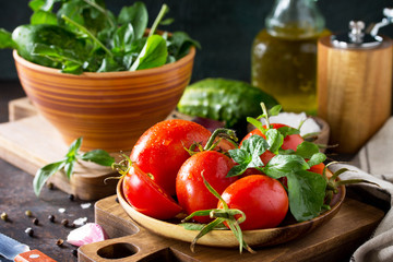 Healthy food: fresh vegetables on the kitchen table in a rustic style. Fresh tomatoes, cucumbers and rucola for cooking salad. Diet menu.