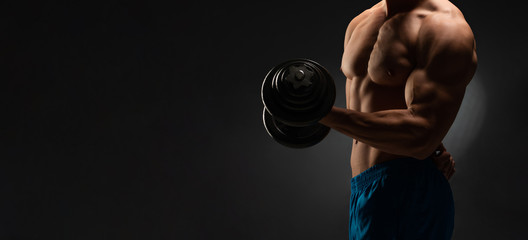 Fototapeta na wymiar athletic young man on a black background with dumbbells - plenty of space for your own text, banner, advertising