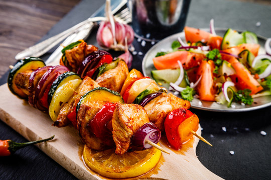 Kebabs - grilled meat with french fries and vegetables on wooden background