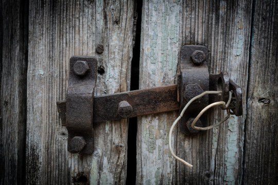 Rusty door bolt on grey wooden door