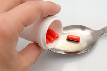 Red capsules pill spilled out of white plastic bottle. Global healthcare concept. Antibiotics drug...