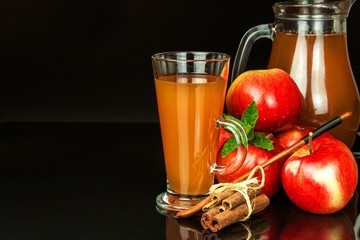 Fresh apple juice in a glass. Fruit harvest. Healthy beverage. Apples on the kitchen table. Production of juice. On a black background.