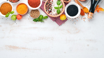 A set of Spices and herbs on a white wooden table. Basil, pepper, saffron, spices. Indian...