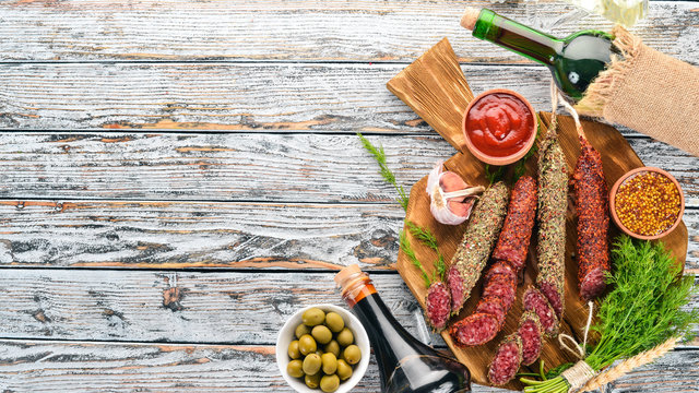 Fuete sausage, salami, paperoni on the kitchen blackboard. On a white wooden background. Top view. Free space for your text.