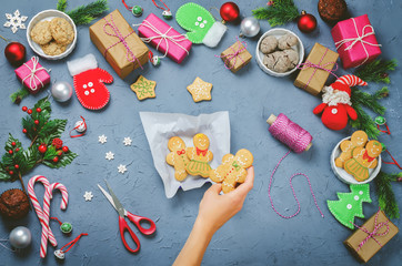 Christmas background with gifts, cookies, Christmas decoration and woman's hands holding cookies