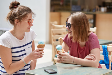 People, lifestyle and rest concept. Joyful hipsters have spare tine, eat delicious ice cream in...