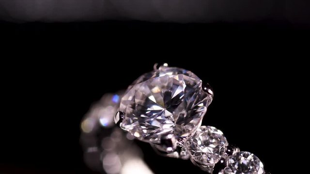 Engagement diamond ring rotating on black background, macro with shallow DoF