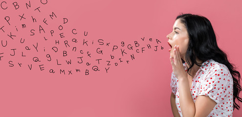 Alphabet letters with young woman speaking on a pink background - obrazy, fototapety, plakaty