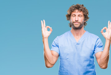 Naklejka premium Handsome hispanic surgeon doctor man over isolated background relax and smiling with eyes closed doing meditation gesture with fingers. Yoga concept.
