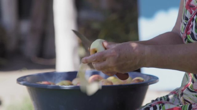 Close-Up of an Elderly Woman's Hand With a Knife Peeled Apple