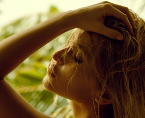 Close up portrait of blonde woman with wet hair on green sunny tropical island background
