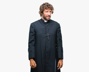 Handsome hispanic catholic priest man over isolated background winking looking at the camera with...