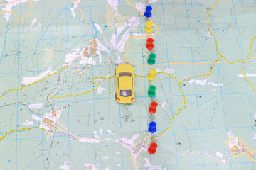 Fototapeta na wymiar The yellow car travels along the coordinates marked on the geographic map. View from above