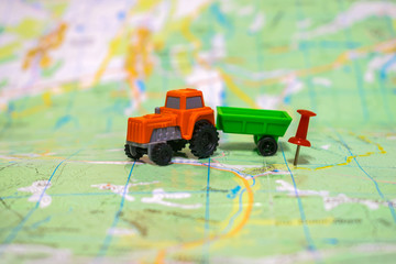The orange tractor moves to the farm. A toy tractor is on a map. The concept of agriculture.
