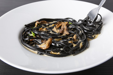 Pasta with wheat germ and black squid ink. Mushroom sauce. Olive oil and spices. Copy space.