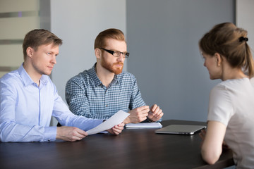 Serious male hr team attentively listening female applicant talking at job interview, focused human...