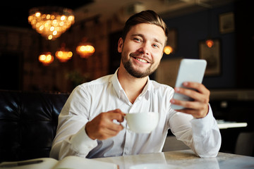 Handsome young businessman with coffee and phone