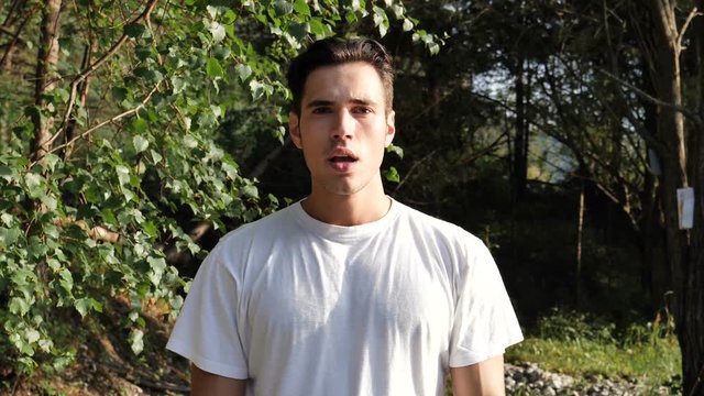 Young handsome man unable to hear you, standing in nature