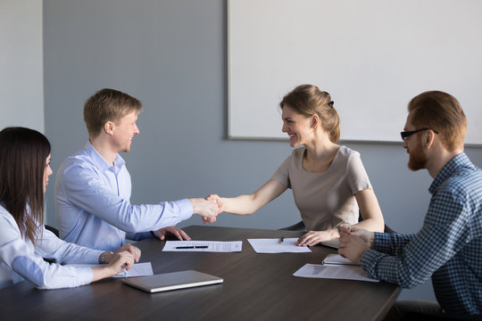 Smiling female and male new partners shaking hands satisfied with successful negotiation result and contract signing, happy business deal parties man and woman celebrating partnership with handshake