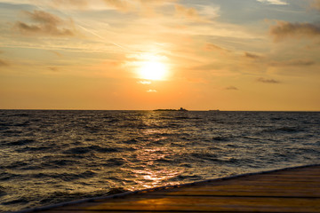 Fototapeta premium Minimalistic orange sunrise over the ocean with waves near the shore