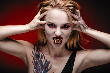 Halloween girl vampire with red eyes red lips and red background. Scary woman trick or treat time,...