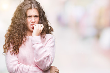 Beautiful brunette curly hair young girl wearing pink winter sweater over isolated background looking stressed and nervous with hands on mouth biting nails. Anxiety problem.