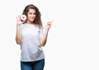 Young brunette girl eating donut over isolated background very happy pointing with hand and finger to the side