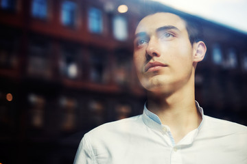 Pensive handsome elegant man behind window