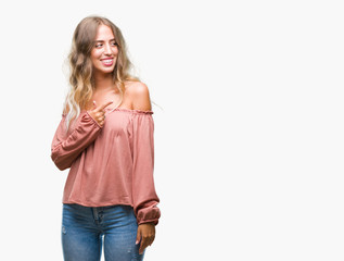 Fototapeta premium Beautiful young blonde woman over isolated background cheerful with a smile of face pointing with hand and finger up to the side with happy and natural expression on face looking at the camera.