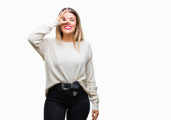 Young beautiful woman casual white sweater over isolated background doing ok gesture with hand smiling, eye looking through fingers with happy face.