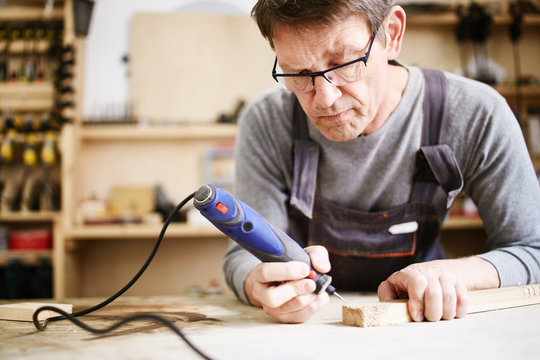 Focused man carving with electric chisel