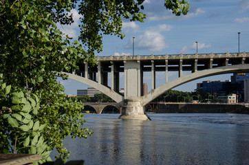 Fototapeta na wymiar Daytime view of the I-35W Bridge in downtown Minneapolis with the Mississippi River in the foreground. Summer